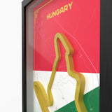 A framed Hungary-themed wall art print with a large 3D gold outline of the country's shape over a red, white, and green flag background and faint map lines. The word HUNGARY appears at the top.Detailed Hungaroring track 3D printed layered side view