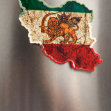 Fridge magnet shaped like a map of iran with a lion emblem on a metallic surface